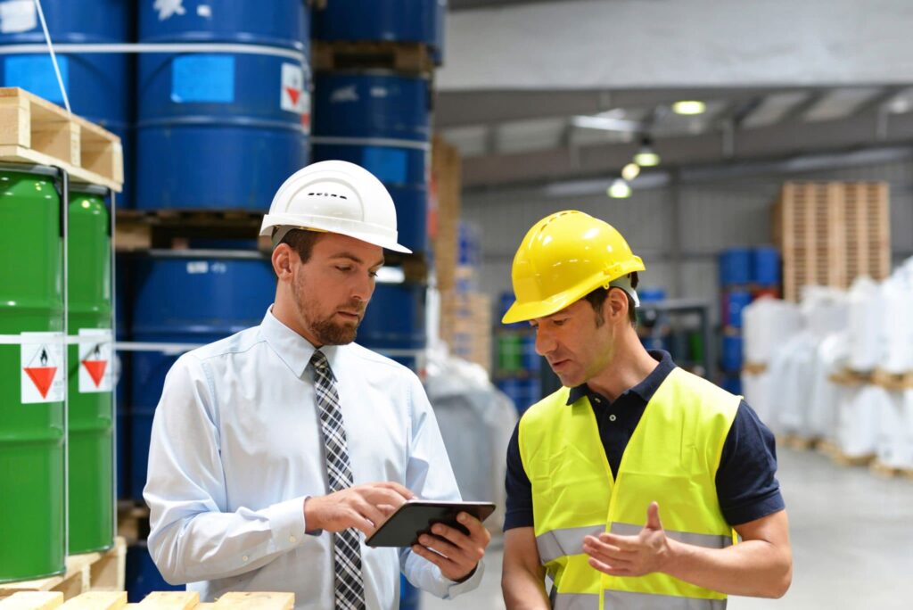 two men wearing hard hats in a manufacturing warehouse