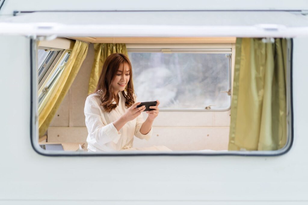 a woman using the Vista Connect app on her phone to control lighting while in an RV